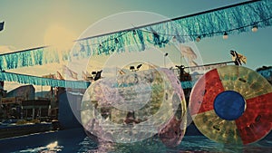 2 Inflatable Water Rollers. Water attractions. Children playing inside an inflatable roller. Amusement park. Sunset.