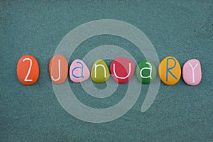 2 January, calendar date composed with multi colored stone letters over green sand