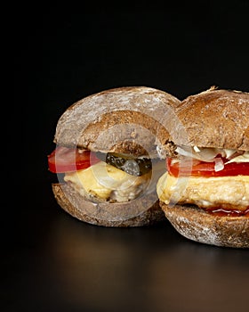 2 juicy burgers with vegetables and a large chicken cutlet in dark background ,fast food cheeseburgers