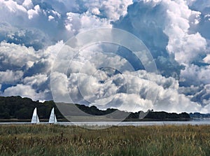 2 little white sails and big towering clouds