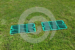 2 manhole drainage grates on the lawn with green grass septic tank.