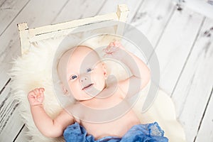 2 month baby smiling covered with blue textile