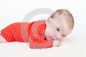 2 months baby girl in red bodysuit lying on belly