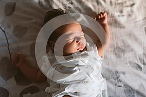 2 months old newborn baby sleeping peacefully in bed in the morning with natural light with white pijama