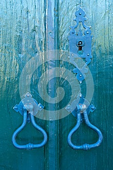 2 old iron locks of blue green color equal to the color of the wooden door
