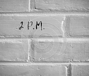 2 P.M. WRITTEN ON WHITE PLAIN BRICK WALL