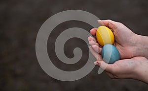 2 Painted eggs for Easter in the colors of the flag of Ukraine in the hands, which symbolizes PEACE IN UKRAINE