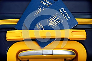 2 passports of citizens of Ukraine lie on yellow blue suitcase in color of Ukrainian flag at border. Travel concept, refugees,