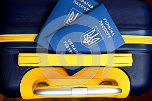 2 passports Ukraine with inscription in Ukrainian - Passport of Ukraine lie on yellow-blue suitcase in color of Ukrainian flag.