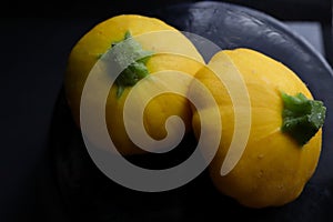 2 pattypan summer squash on a dark background