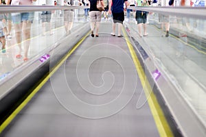 2 people walking on a straight forward goin escalator