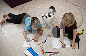 2 preschool boys, brothers or friends, draw with pencils on the floor of the children`s room