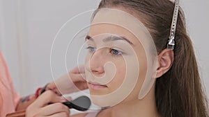 2 shots. Professional make-up artist applying powder to woman face