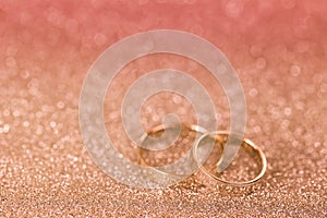 2 silver rings on glittery background with pink filter and copyspace