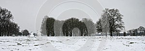2 snow people in a field with sticks that look like they are holding hands. A winter scene