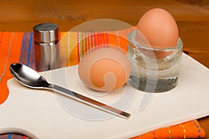 2 soft-boiled eggs on a wooden board.
