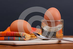 2 soft-boiled eggs on a wooden board.