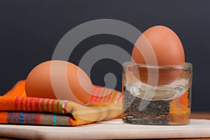 2 soft-boiled eggs on a wooden board.