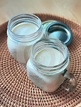 2 Two glasses of mason jars with natural homemade plain yoghurt, yogurt, on the handwoven rattan tray, wicker basket,
