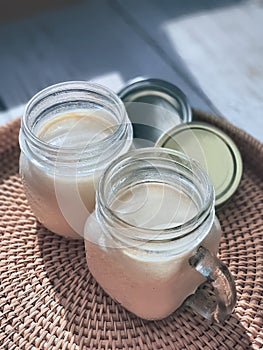 2 Two glasses of mason jars with natural homemade plain yoghurt, yogurt, on the handwoven rattan tray, wicker basket,