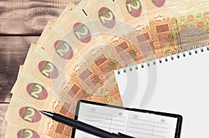 2 Ukrainian hryvnias bills fan and notepad with contact book and black pen. Concept of financial planning and business strategy
