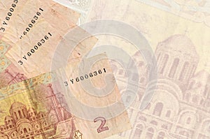 2 Ukrainian hryvnias bills lies in stack on background of big semi-transparent banknote. Abstract business background