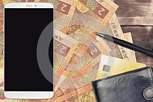 2 Ukrainian hryvnias bills and smartphone with purse and credit card. E-payments or e-commerce concept. Online shopping and
