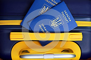 2 Ukrainian passports with inscription in Ukrainian - Passport of Ukraine lies on yellow blue suitcase. Travel concept, refugees,