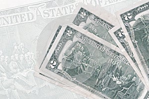 2 US dollars bills lies in stack on background of big semi-transparent banknote. Abstract presentation of national currency