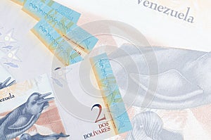 2 Venezuelian bolivar bills lies in stack on background of big semi-transparent banknote. Abstract business background