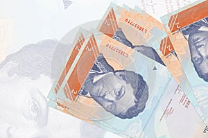 2 Venezuelian bolivar bills lies in stack on background of big semi-transparent banknote. Abstract presentation of national