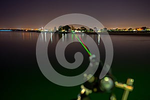 2 visible beams of laser light, red and green, focusing in the direction of Lisbon, crossing the Tagus River from Barreiro.