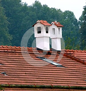 2 white chimneys plastered with brick cover on a tiled roof  3