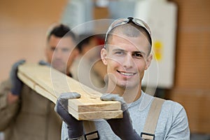 2 workers carrying wooden planks