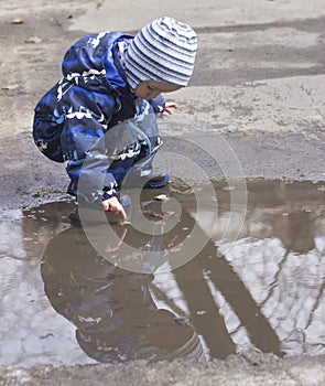 A 2 -year-old boy playing with in a puddle