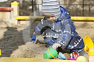 A 2-year- old boy playing in a sandbox