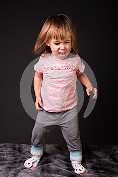 2 year old child looking angry standing isolated on white background. Cutout photo for concept of emotions development