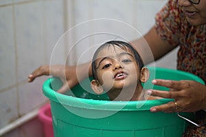 2-year-old Indian baby boy enjoying a bath in a green tub.