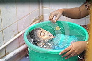 2-year-old Indian baby boy enjoying a bath in a green tub.