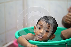 2-year-old Indian baby boy enjoying a bath in a green tub.