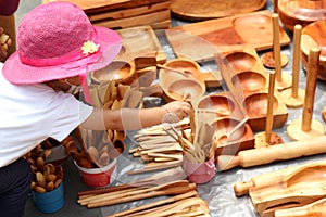 2 year old latin girl with pink hat buying handmade wooden kitchen utensils