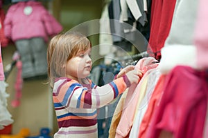 2 years girl chooses dress at shop