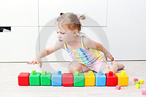 2 years girl playing with multicolored cubes at home on the floor