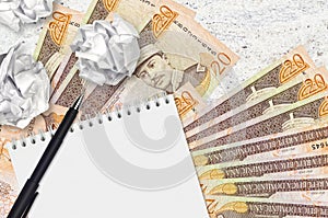 20 Dominican peso bills and balls of crumpled paper with blank notepad. Bad ideas or less of inspiration concept. Searching ideas