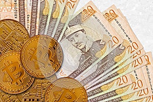 20 Dominican peso bills and golden bitcoins. Cryptocurrency investment concept. Crypto mining or trading