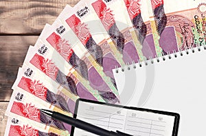 20 Sri Lankan rupees bills fan and notepad with contact book and black pen. Concept of financial planning and business strategy