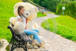 A 20-year-old girl in a park with her huge teddy bear