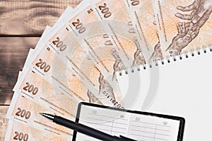 200 Czech korun bills fan and notepad with contact book and black pen. Concept of financial planning and business strategy