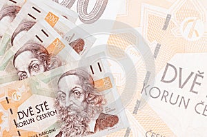 200 Czech korun bills lies in stack on background of big semi-transparent banknote. Abstract business background