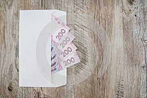 200 hryvnia banknotes in a white envelope on a wooden background. Copy of space. Place for text.